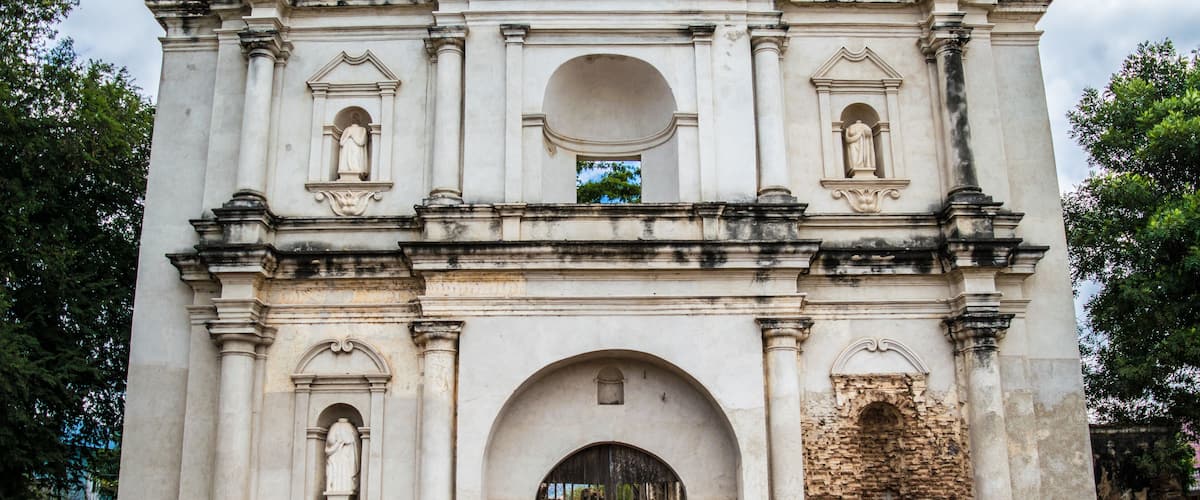 An old, weathered building with arched doorways and statues.