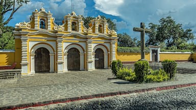 A yellow and white colonial church with a cross in front.