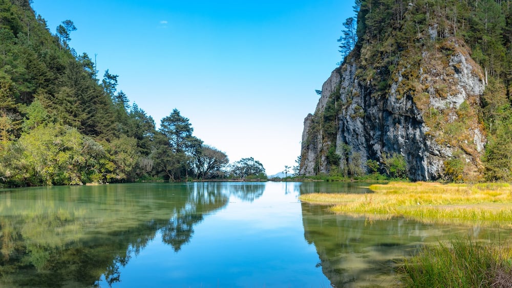 Magdalena Lagoon, in middle of forest, trees and mountain are reflected in the water, in Sierra de los Cuchumatanes, Huehuetenango, Guatemala