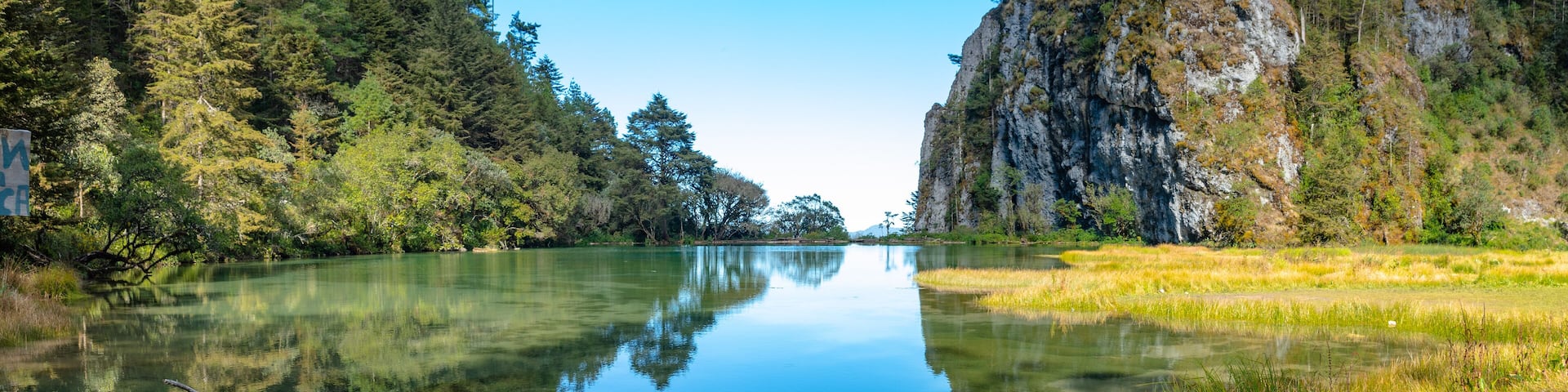 Magdalena Lagoon, in middle of forest, trees and mountain are reflected in the water, in Sierra de los Cuchumatanes, Huehuetenango, Guatemala