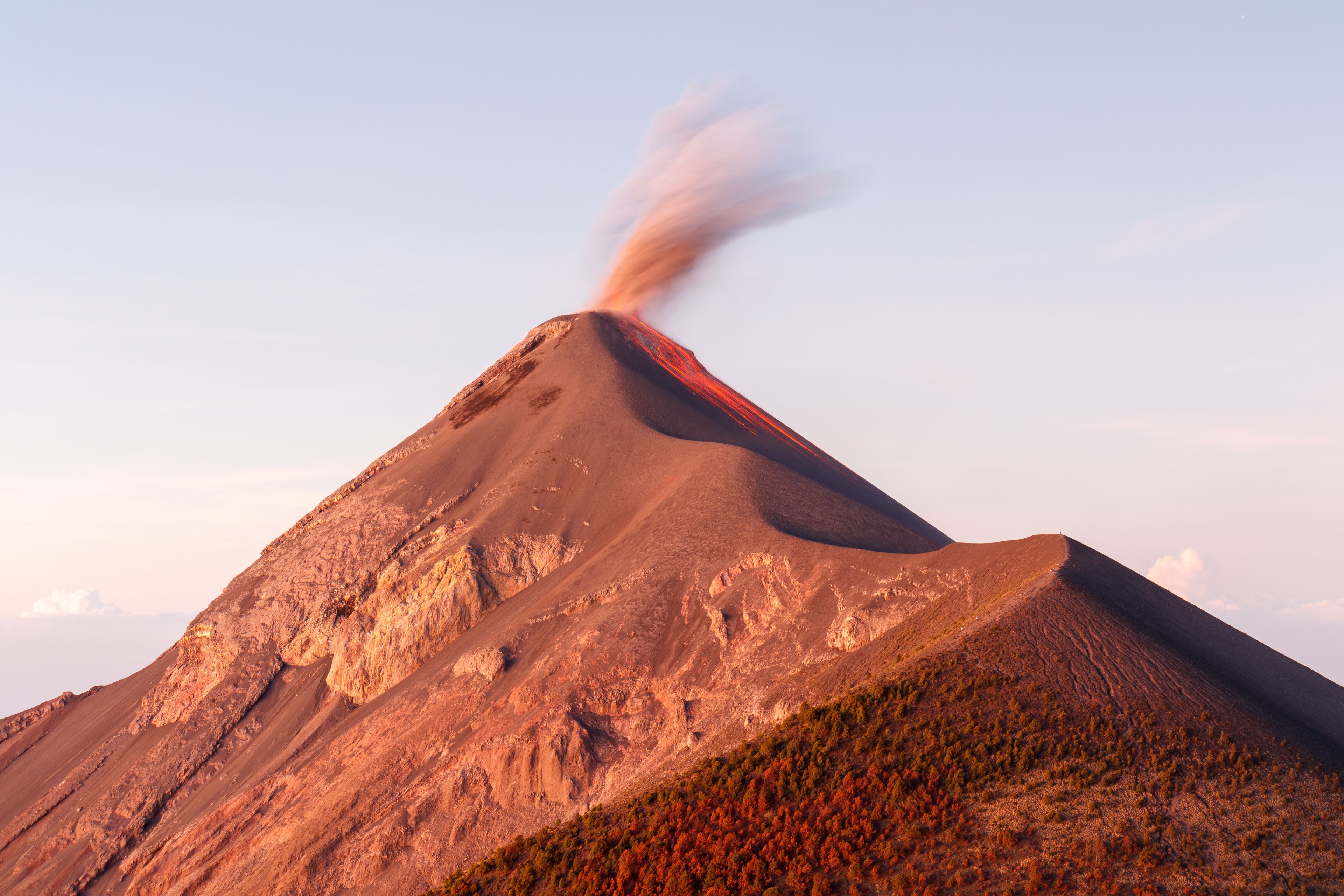 Un volcán con una columna de humo o vapor elevándose desde su cima.