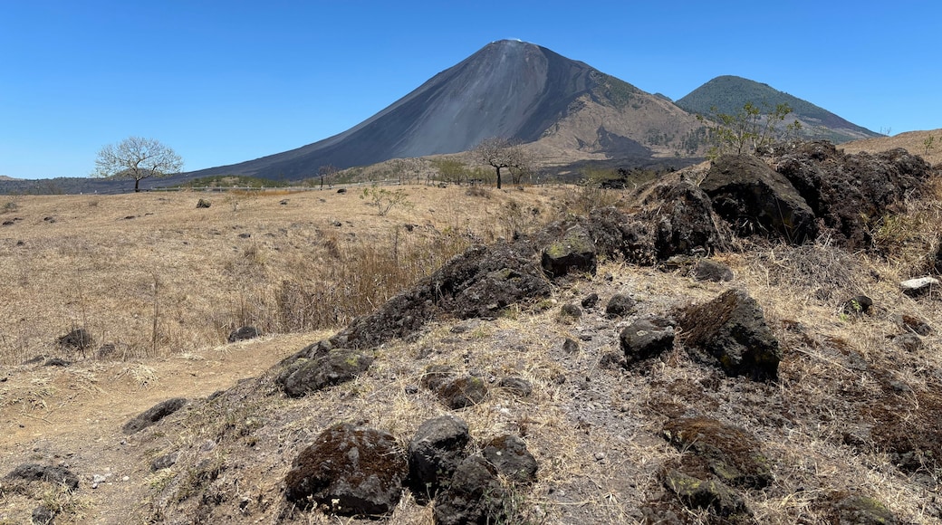 Un paisaje seco y rocoso con una montaña destacada al fondo.