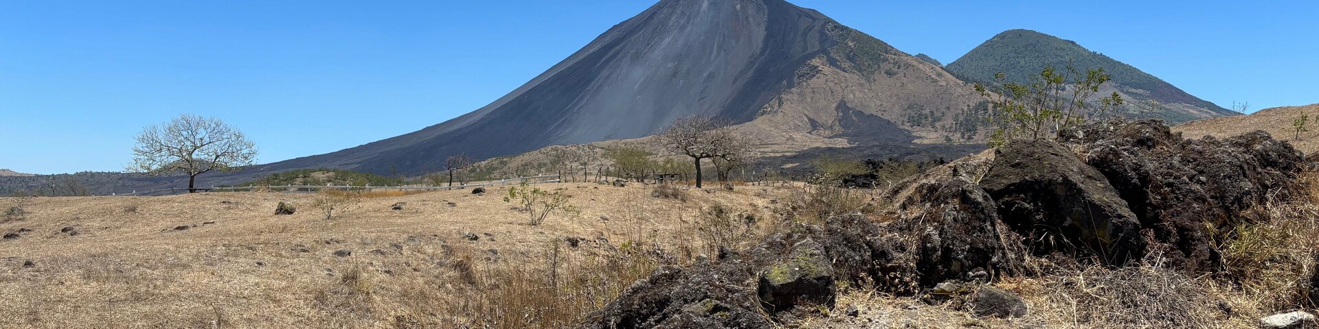 Paisagem árida e rochosa com uma montanha imponente ao fundo.