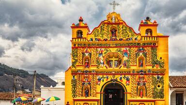Una iglesia colorida con murales detallados y un campanario.