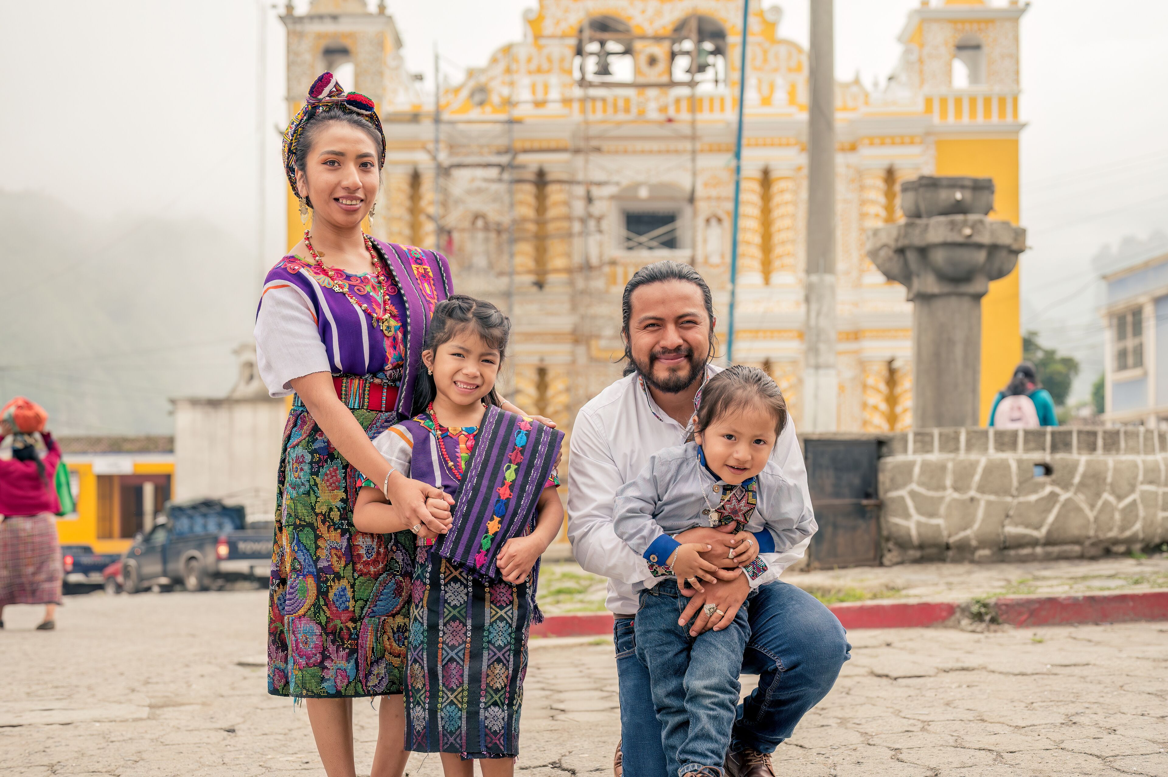 Latin family smiling looking at the camera with their two children.