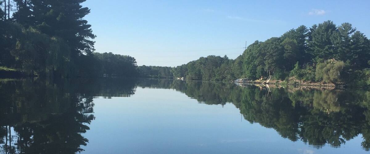 A calm lake with clear reflections of trees and a clear sky.