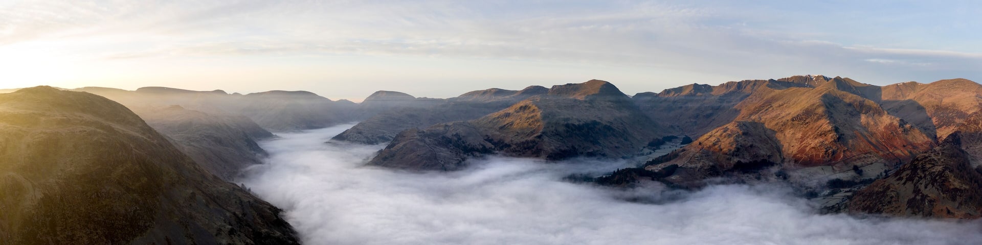 A mountainous landscape with a valley filled with clouds.