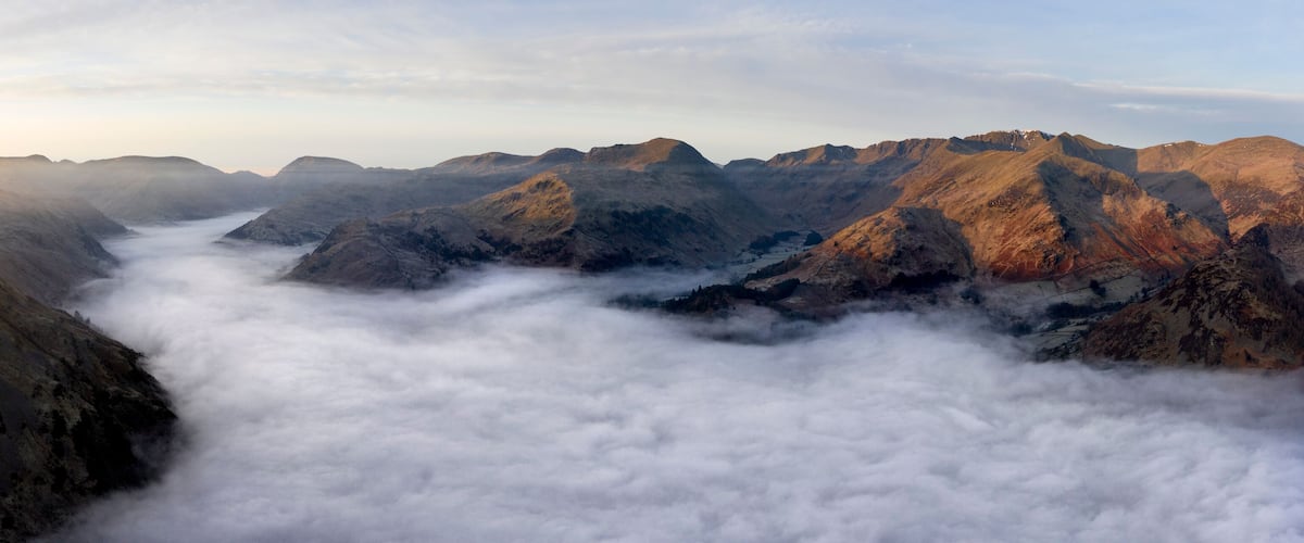 A mountainous landscape with a valley filled with clouds.