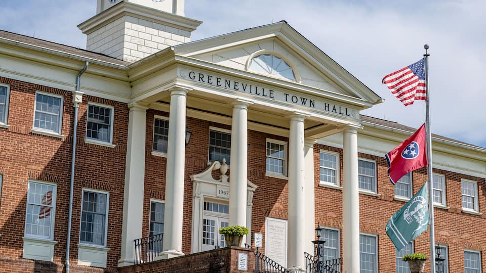 A brick building with a clock tower and columns labeled 'Greenville Town Hall.'