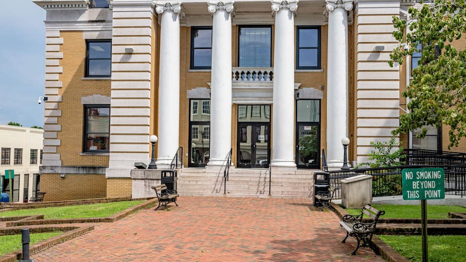 The Greene Co. Courthouse with a brick pathway leading to the entrance, columns, and a 'No Smoking Beyond This Point' sign.