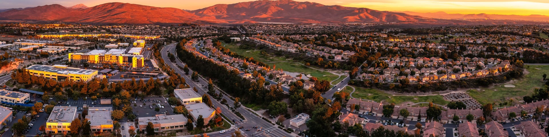 A cityscape with a river, mountains, and autumn foliage.