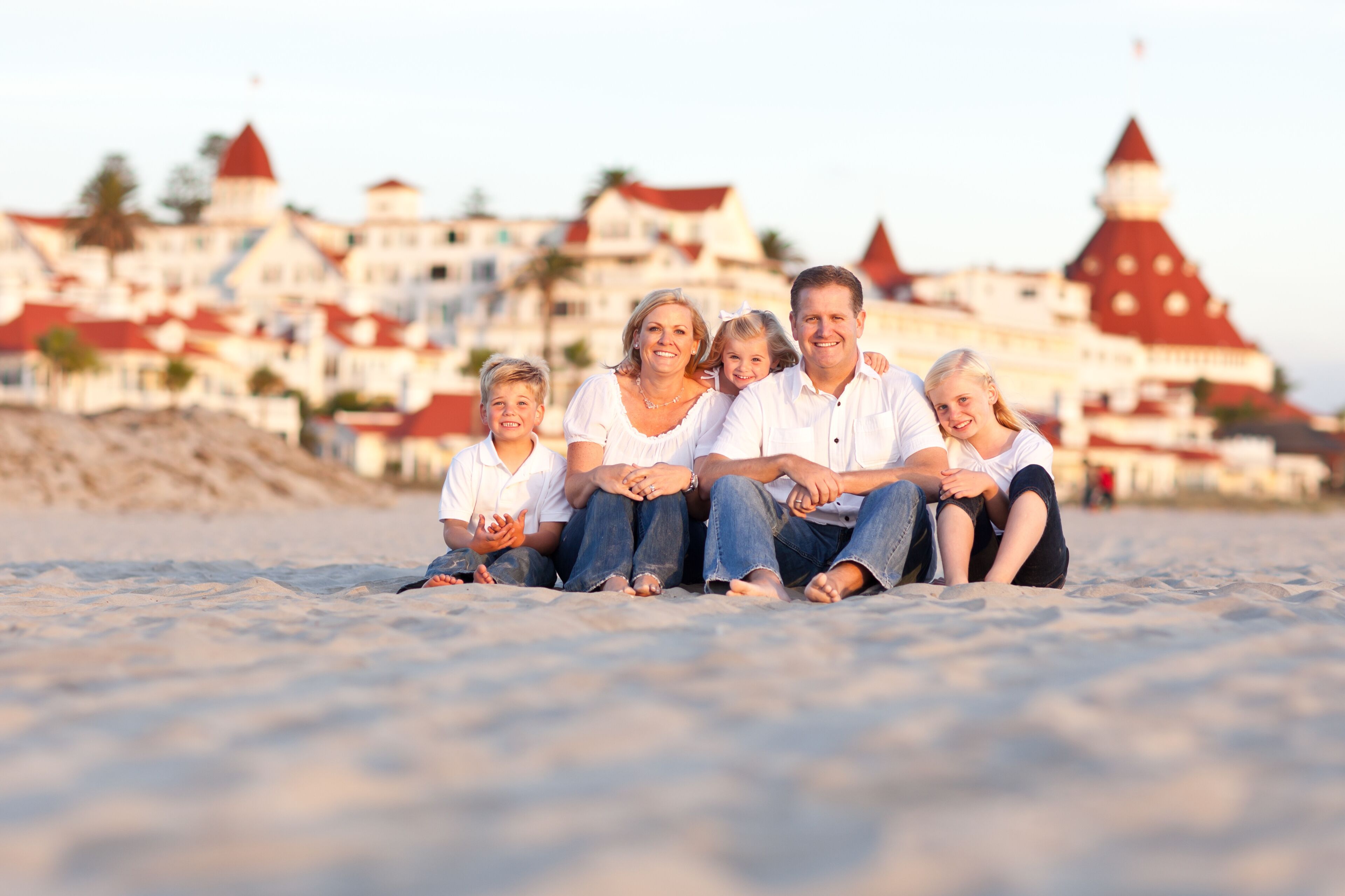 Una familia en una playa arenosa con un edificio histórico al fondo.