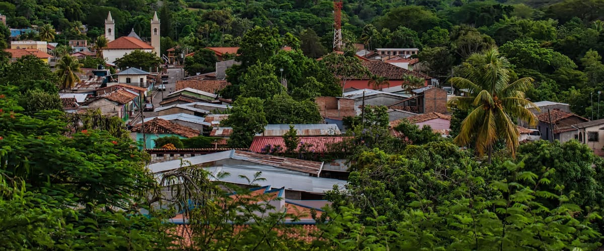 A town nestled in a valley with hills in the background, featuring a church with two towers and a prominent tower structure.