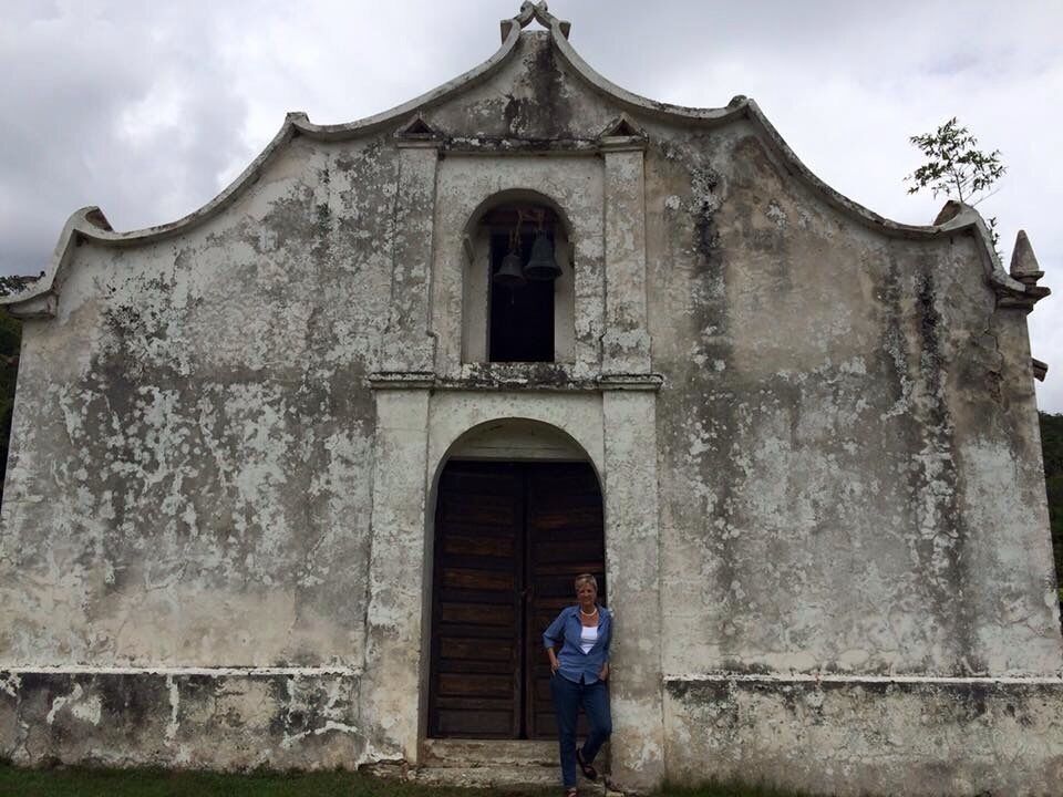 An old, weathered building with a bell tower and arched entrance.
