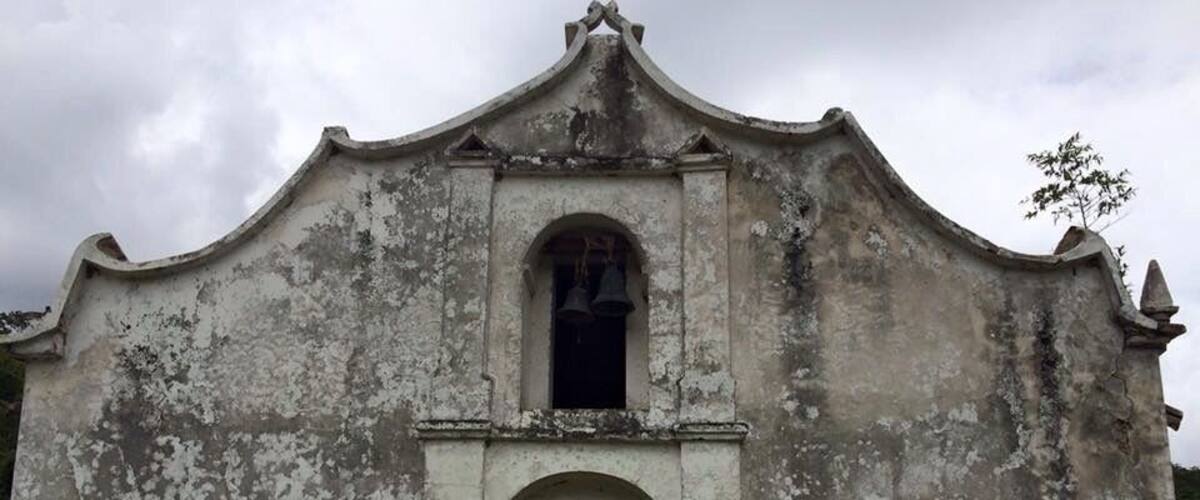 An old, weathered building with a bell tower and arched entrance.