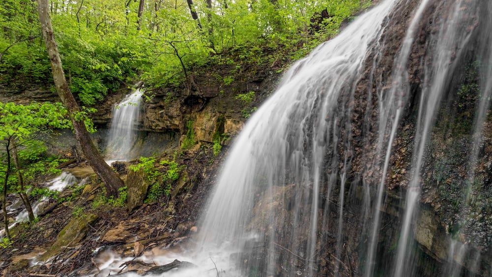 A waterfall cascading over a rocky cliff surrounded by lush green foliage.