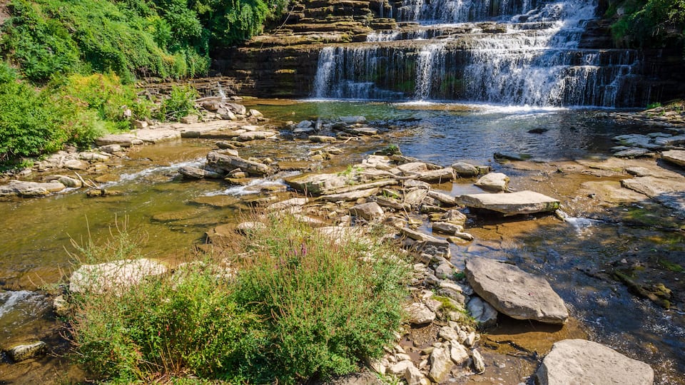 A multi-tiered waterfall surrounded by rocks and greenery.