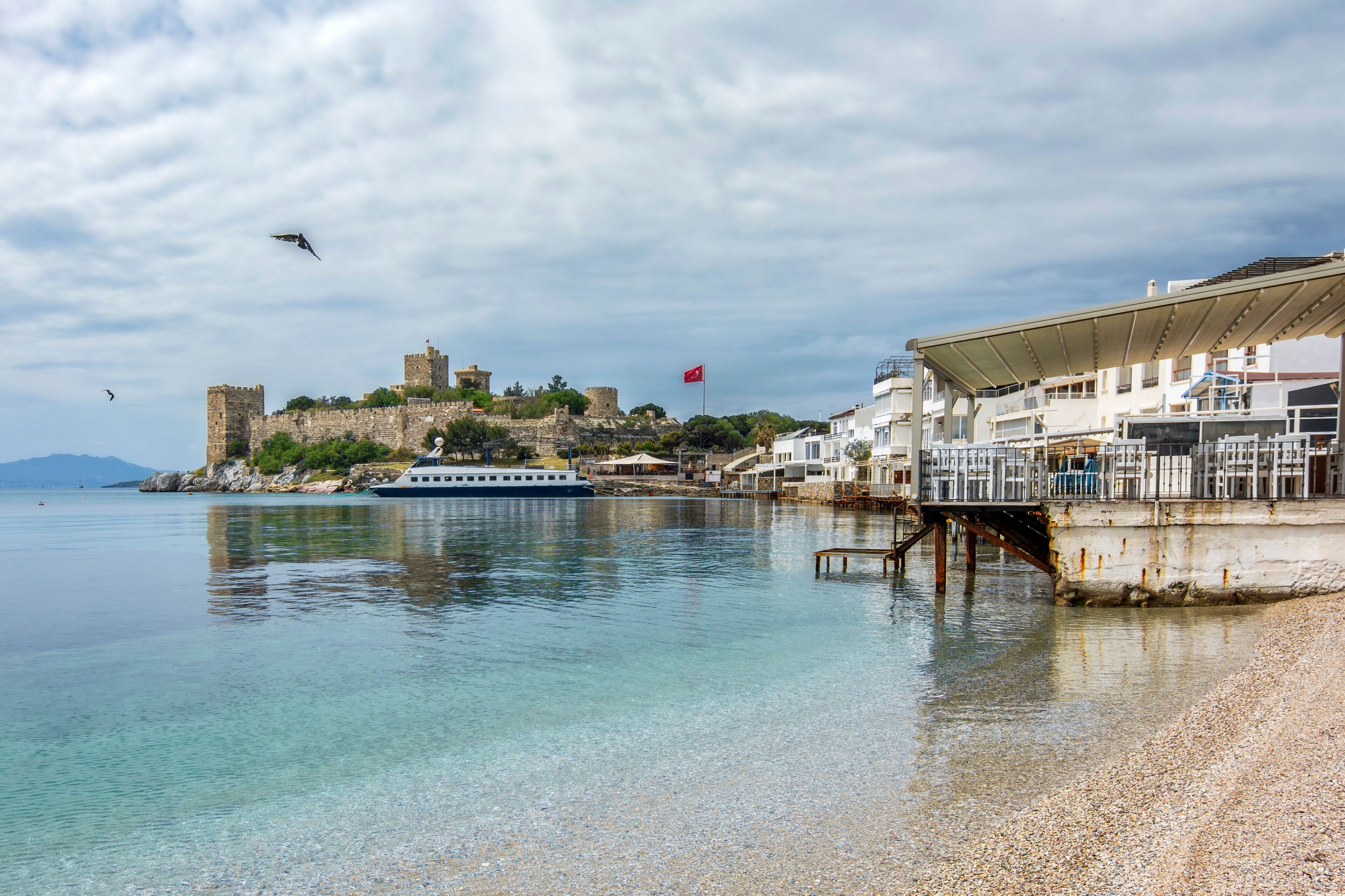 Un pueblo costero con un castillo histórico, un ferry y una playa.