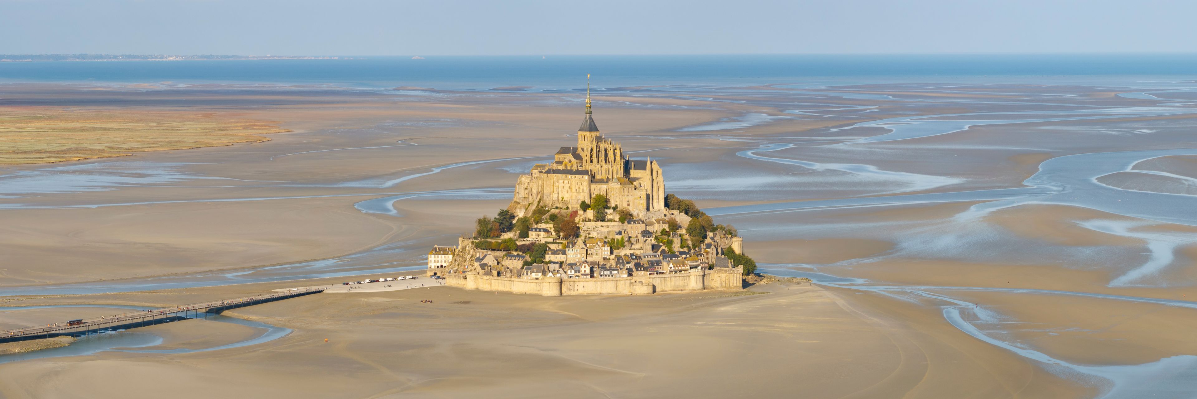 A coastal town with a prominent castle on a hill, surrounded by expansive sandy beaches and tidal flats.