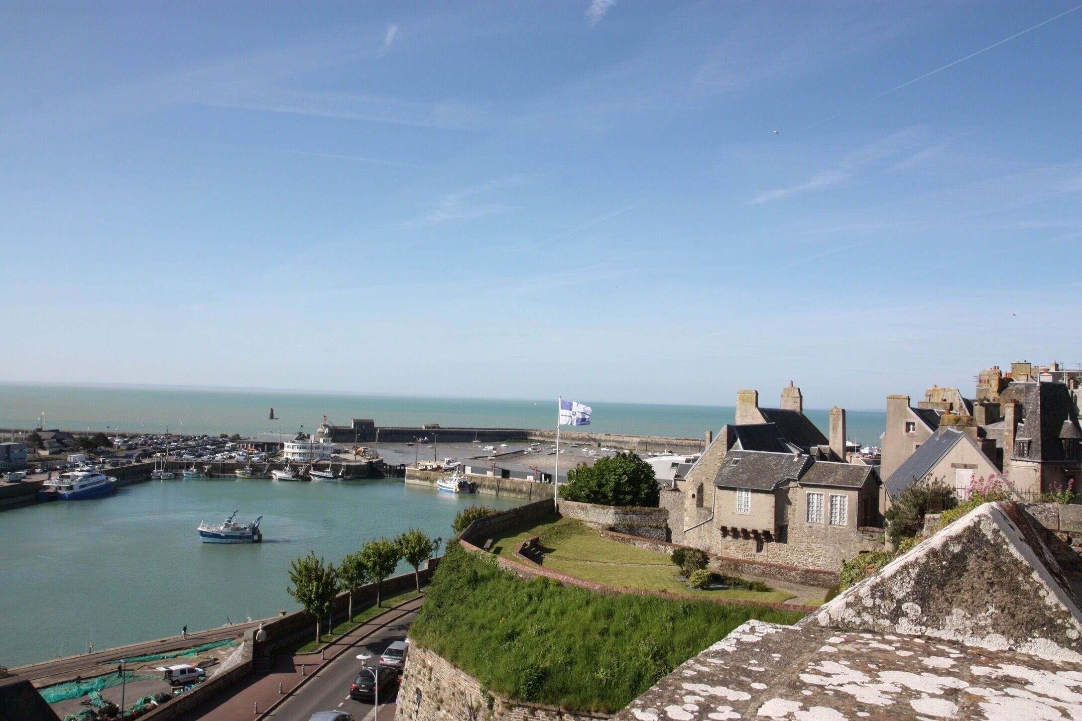 A coastal town with a harbor, historic buildings, and a flag-raising ceremony.