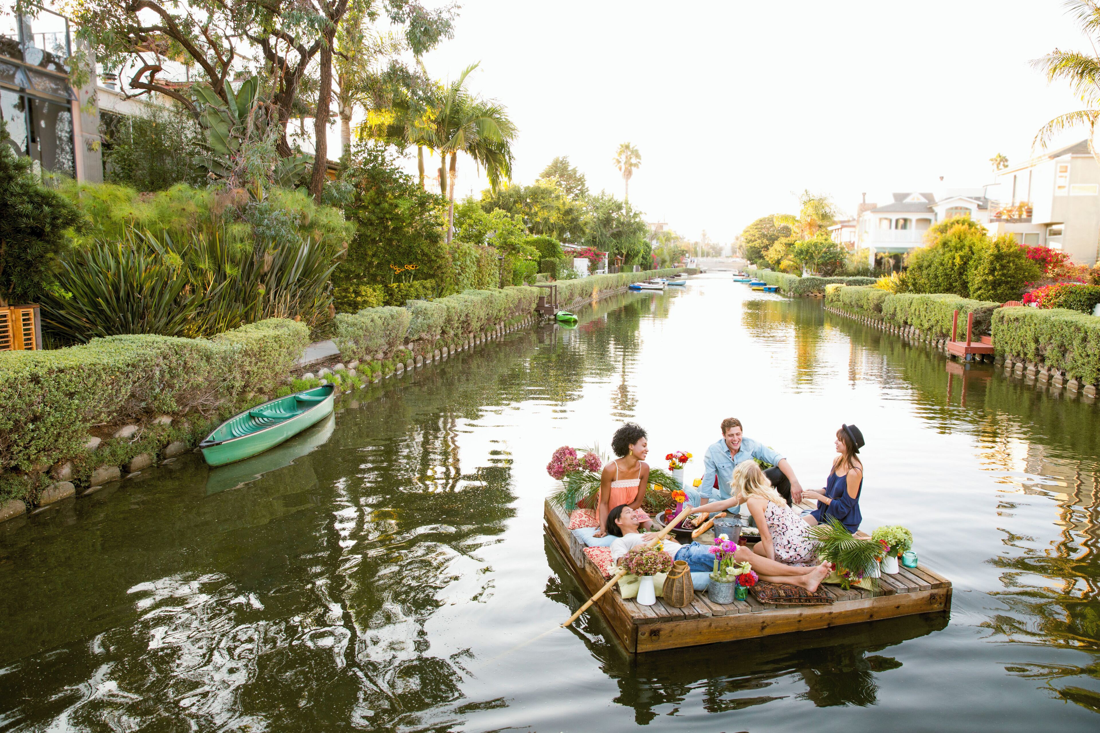 Group of adult friends having a picnic on raft along Venice Canals, Old District,  Los Angeles, California, USA