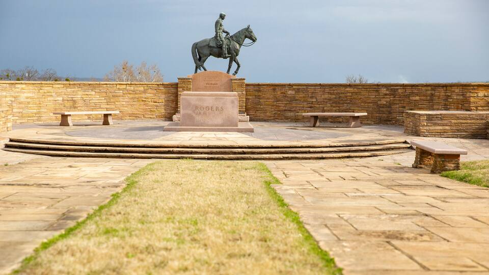 A statue of a man on a horse, a stone bench, and a stone wall.