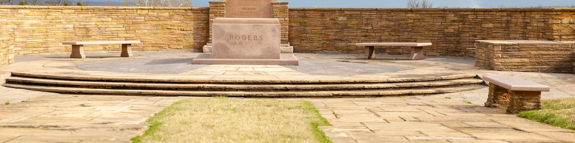 A statue of a man on a horse, a stone bench, and a stone wall.