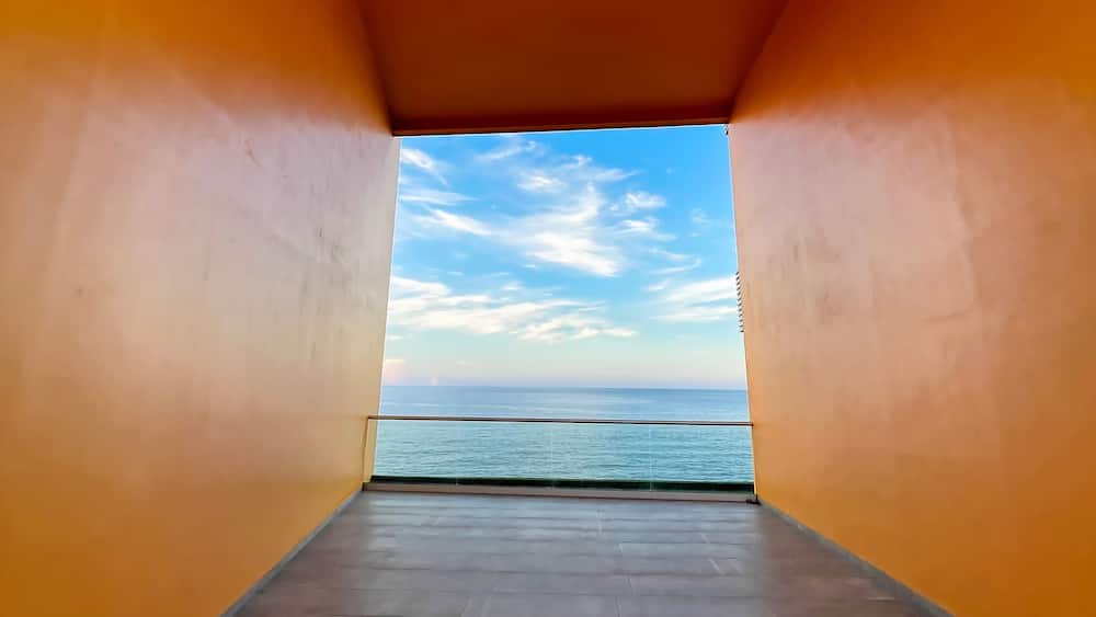 Ein Korridor mit orangefarbenen Wänden und Meerblick.