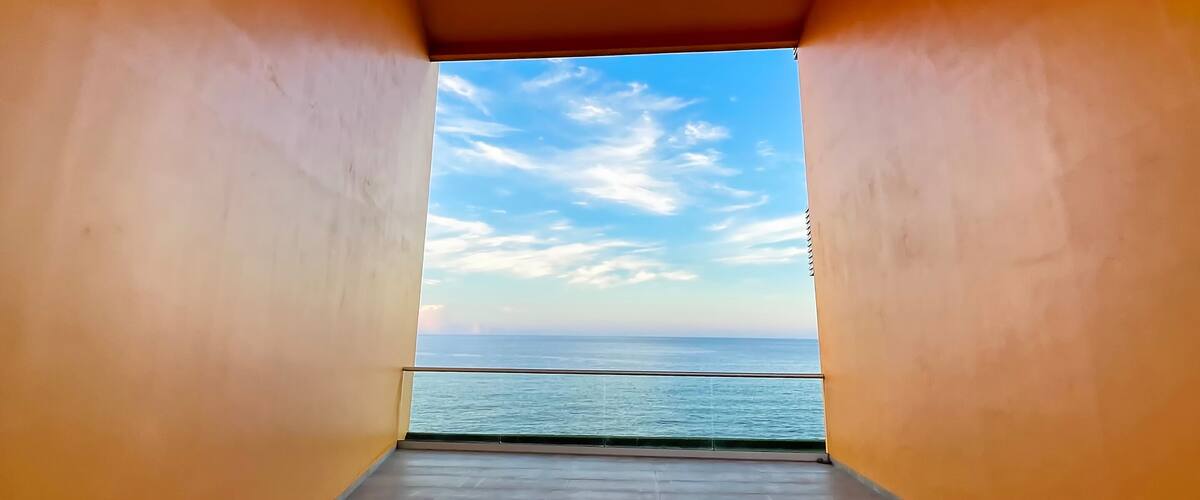 Bright orange corridor with clean geometric lines framing a calm Pacific Ocean view in La Libertad, El Salvador. Minimalist architecture, travel and copy space concept.