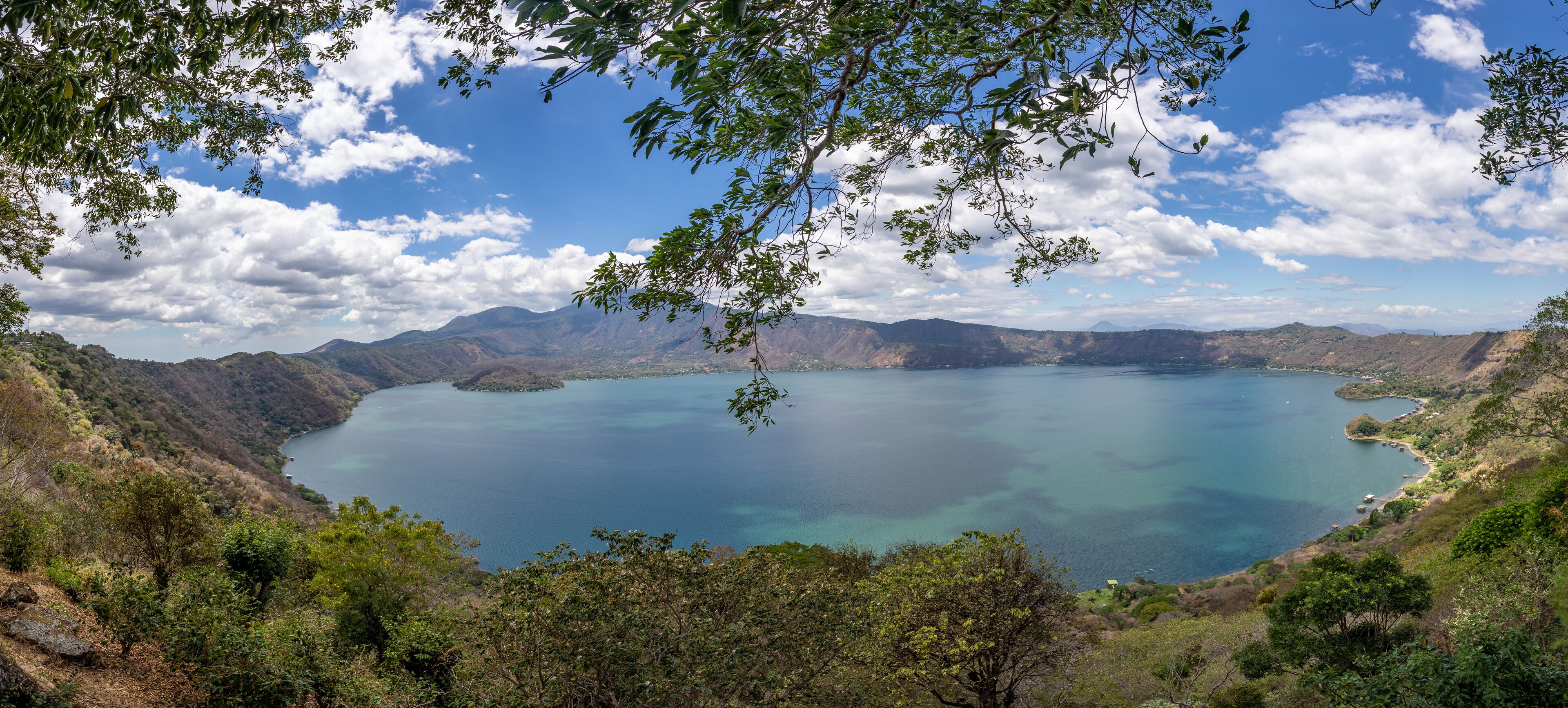 A large lake surrounded by mountains and dense forest.