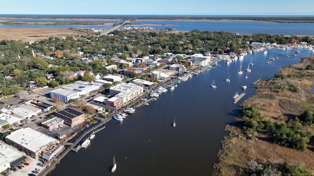 A coastal town with a marina, boats, and a mix of residential and commercial buildings.
