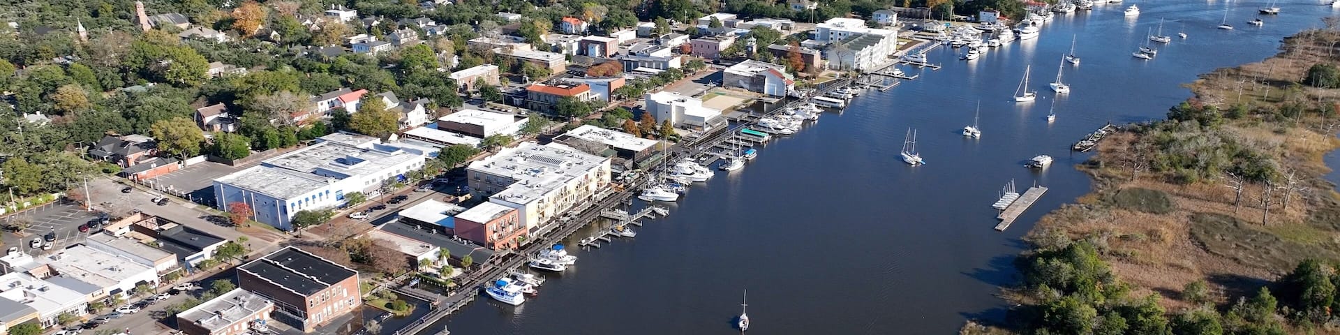A coastal town with a marina, boats, and a mix of residential and commercial buildings.