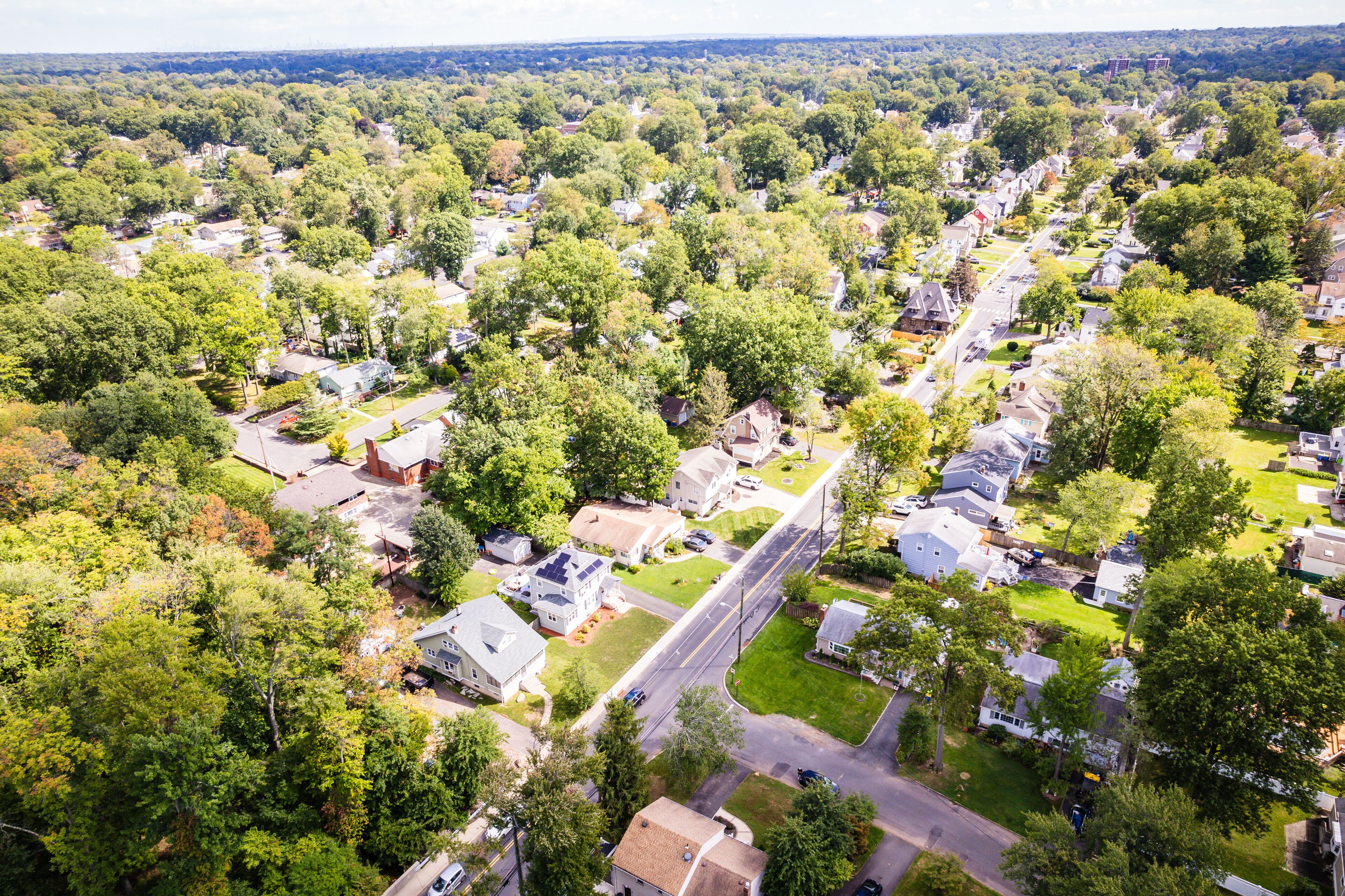 An aerial view of a suburban neighborhood with houses, roads, and surrounding greenery.