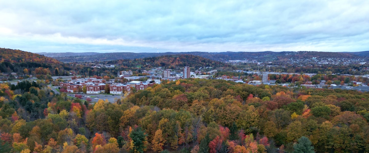 arial view of binghamton university in vestal, new york during autumn with fall foliage (leaves changing colors) at dusk, sunset, cloudy sky (library tower, student union, mountainview residence hall)