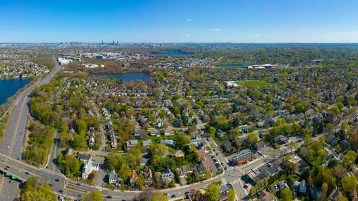 Arlington Heights suburban landscape panoramic aerial view in spring with Spy Pond and Boston modern city skyline at the background in historic town of Arlington, Massachusetts MA, USA.