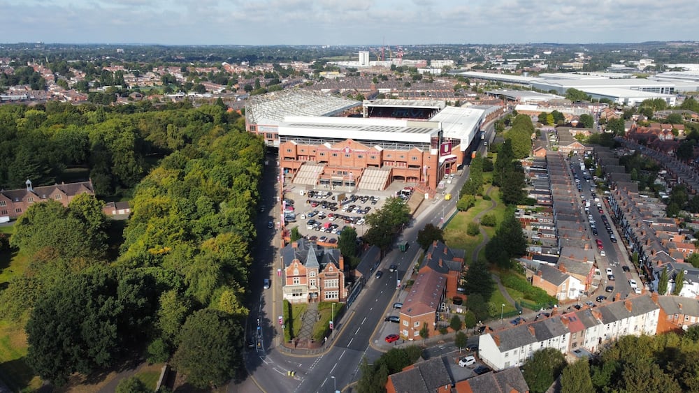 An aerial view of a city with a large stadium, residential areas, and a mix of commercial buildings.