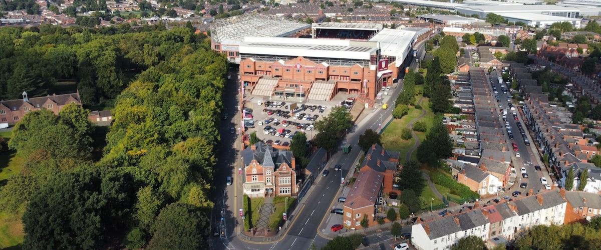 An aerial view of a city with a large stadium, residential areas, and a mix of commercial buildings.