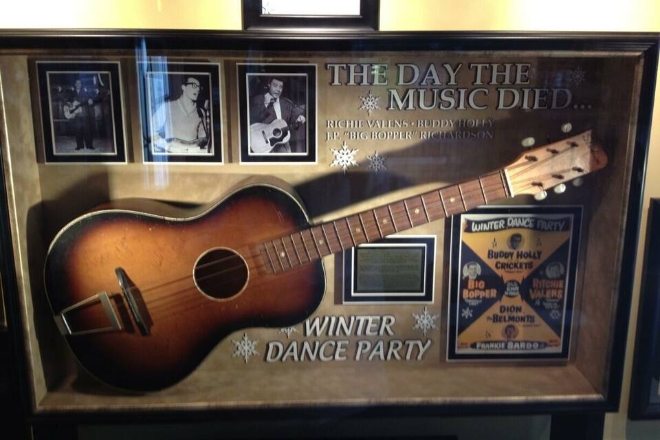 A framed guitar with a Winter Dance Party poster.