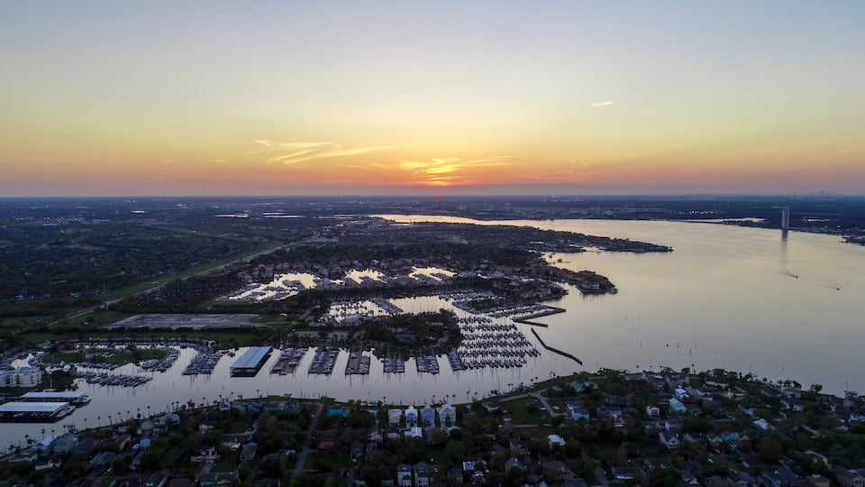 A sunset over a marina with boats, a bridge, and residential areas.