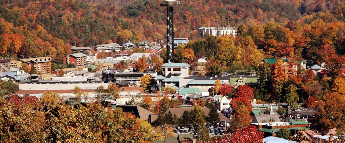 A town nestled in a valley with autumn foliage, surrounded by mountains.
