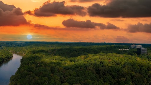 a stunning aerial panoramic shot of the Chattahoochee river surrounded by lush green and autumn colored trees with powerful clouds at Cochran Shoals Trail in Marietta USA