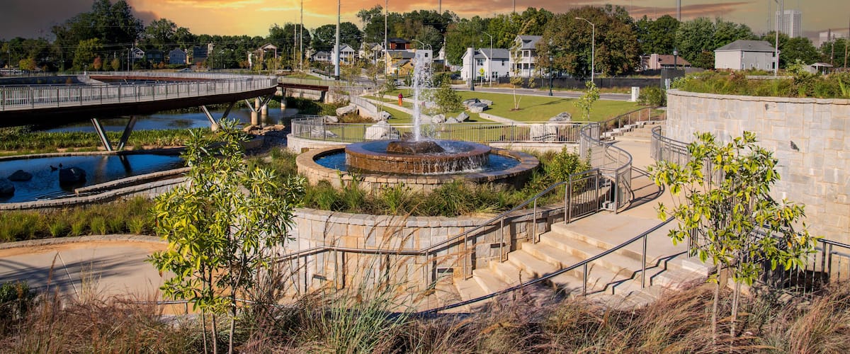 a gorgeous autumn landscape at Rodney Cook Sr. Park in Historic Vine City with water fountains surrounded by lush green trees, grass and plants with powerful clouds at sunset in Atlanta Georgia USA