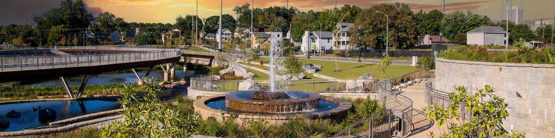 a gorgeous autumn landscape at Rodney Cook Sr. Park in Historic Vine City with water fountains surrounded by lush green trees, grass and plants with powerful clouds at sunset in Atlanta Georgia USA