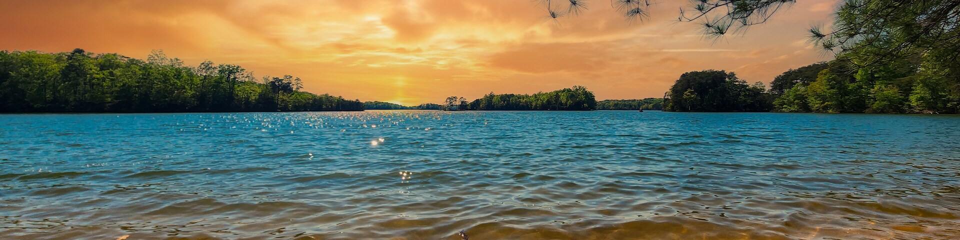 a gorgeous spring landscape at Lanier Point Park with rippling blue water surrounded by lush green trees and plants with powerful clouds at sunset at Lake Lanier in Gainesville Georgia USA