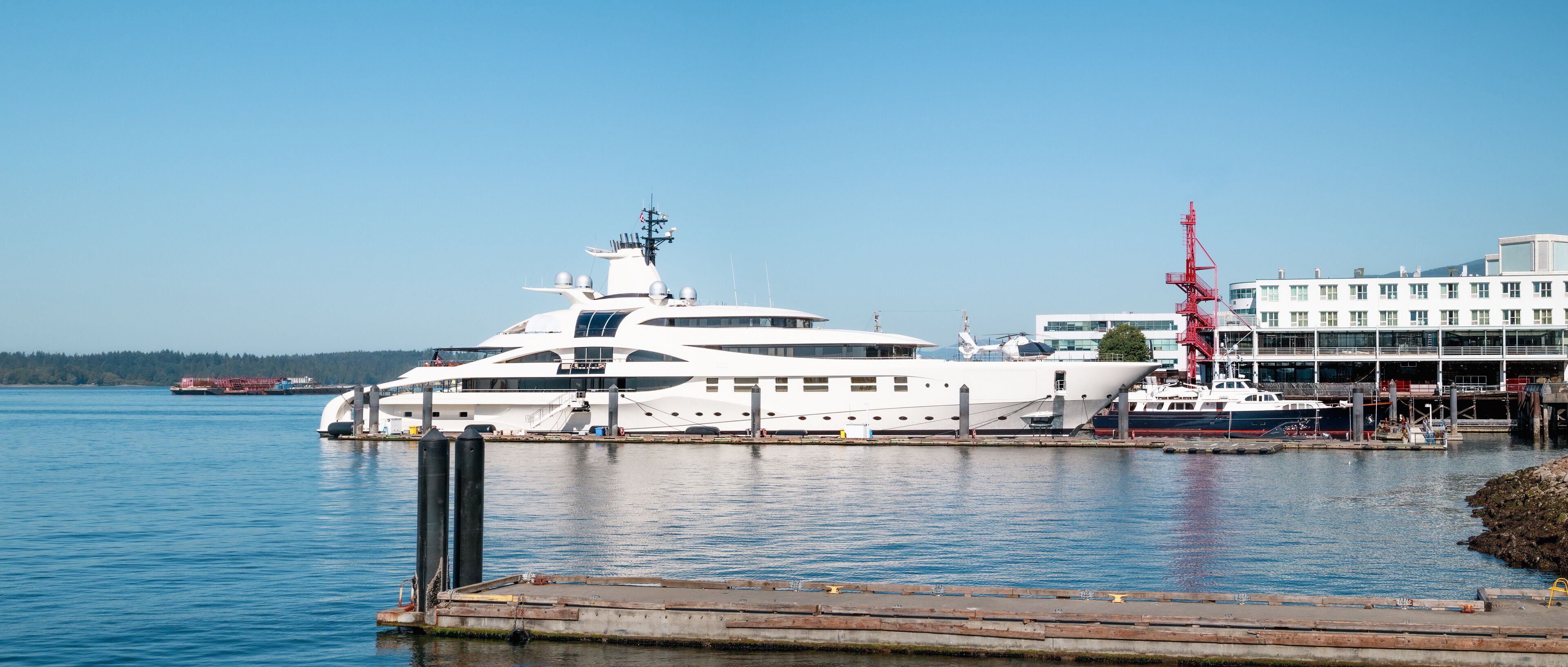 Luxury yacht docked in harbor with buildings. Sideview of long motor yacht. Privat travel background, summer holiday. North Vancouver, BC, Canada. Pacific Ocean. Selective focus.