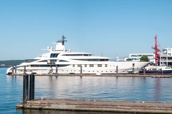 Luxury yacht docked in harbor with buildings. Sideview of long motor yacht. Privat travel background, summer holiday. North Vancouver, BC, Canada. Pacific Ocean. Selective focus.