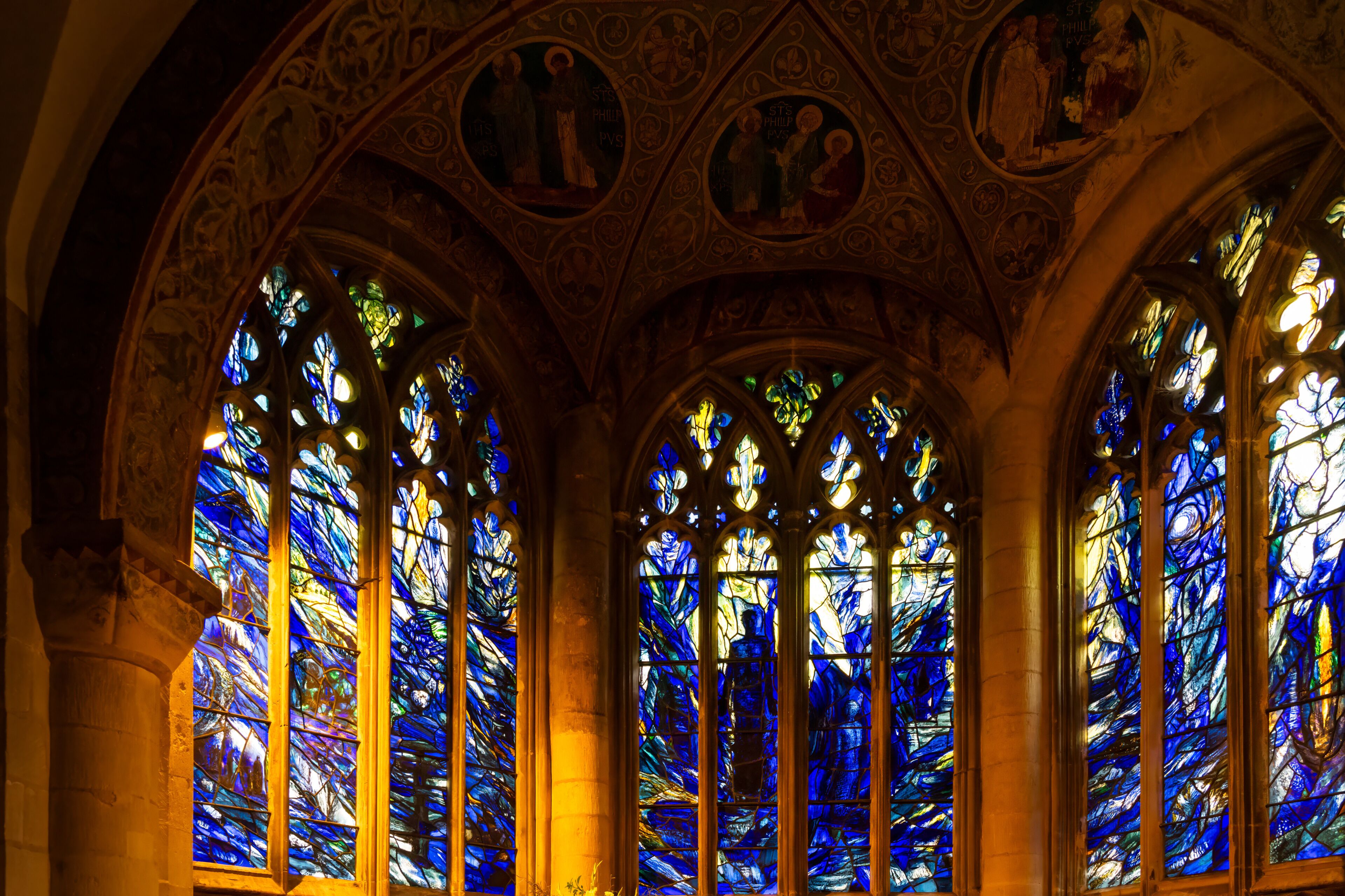 A cathedral interior with stained glass windows and ornate ceiling artwork.