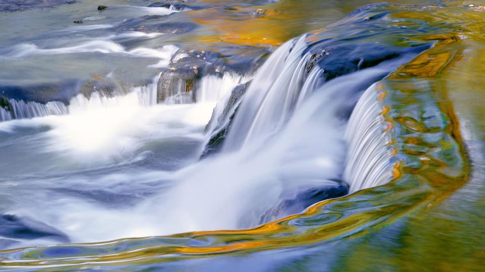 Time exposure of autumn colors reflected in waters of small cascade waterfall in Michigan