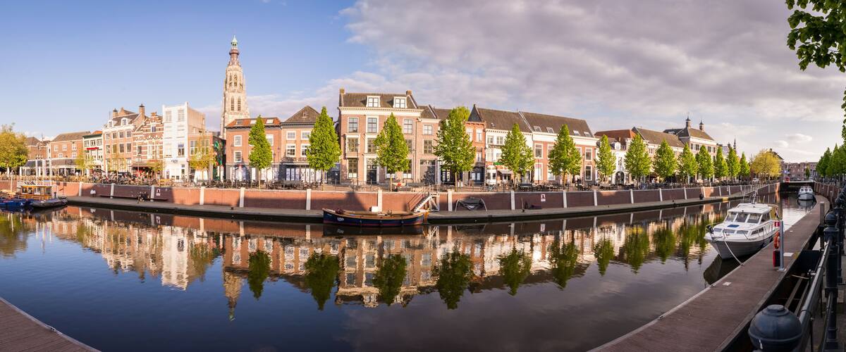 A canal with boats, a historic building, and a church tower.
