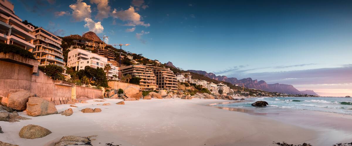 A coastal town with beachfront buildings, a sandy beach, and rocky outcrops.
